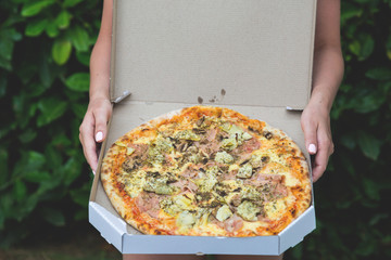 Pizza with prosciutto and artichokes in a box