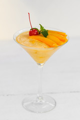 Mango sorbet with mango slices in a glass on the white background