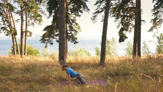 Young man practicing yoga ln the wood. Upward facing dog in the woods by the river