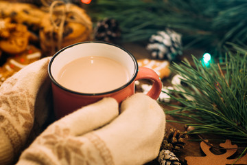 Warm Christmas holiday with latte and cookies. Close up unrecognizable woman with cup of drink in...