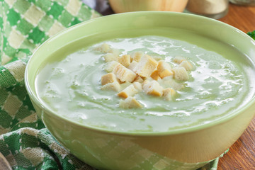 Broccoli cream soup in green bowl served with croutons