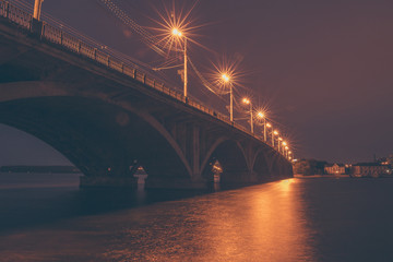 Fototapeta na wymiar Vogresovsky Bridge through Voronezh river at night, dark cityscape