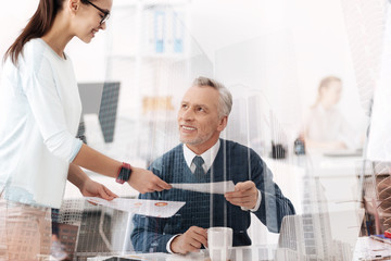 Obraz premium Cheerful professional man working in the office with his young colleague