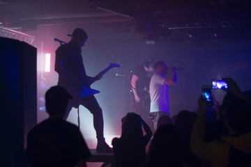 Fototapeta premium Guitarist on a stage playing rock to the crowd of people.