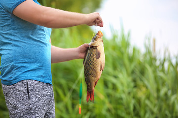 Man with freshly caught fish on river bank