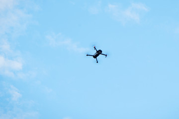 Modern drone hovering in blue sky