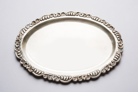 Stock photo of empty or blank silverware or oval shape plate with decorative border, isolated over white background, selective focus
