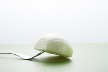 Fresh bulbs of half onion in a fork on a green table