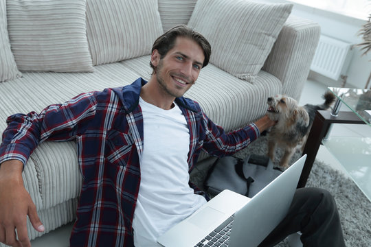 successful guy stroking his pet sitting on the floor near the sofa