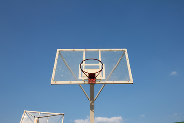 Basketball basket with transparent backboard on beautiful sky 