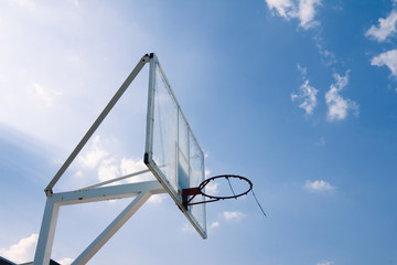 Basketball basket with transparent backboard on beautiful sky 