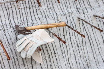 Leather safety gloves and hammer on construction working site background