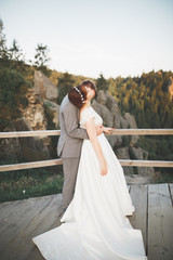 Kissing wedding couple staying over beautiful landscape