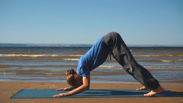 Young man practicing yoga ln the beach. Upward facing dog