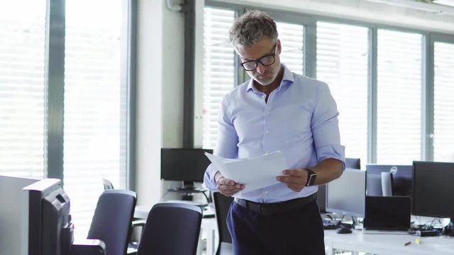 Mature businessman in the office holding documents.