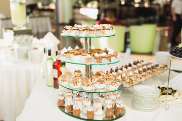 Delicious and tasty dessert table with cupcakes shots at reception closeup