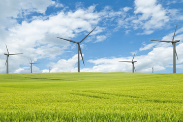 Seven windmills on a green meadow under blue sky with clouds