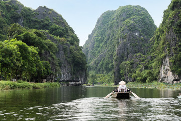 Activity downstream on boat with vietnamese using foot paddle and view limestone mountain in Ngo Dong river