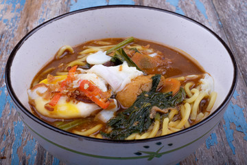 Top view of Mee Bandung on old wooden table .The Noodle is prepared with special curry mixed with prawn and seafood.