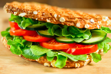 Healthy grilled vegan sandwich made of sprouted organic bread, tomato, cucumber, spinach and arugula. Selective focus