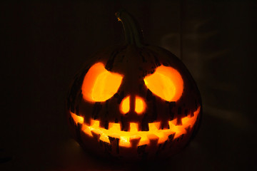 Halloween pumpkin, highlighted by a candle on a black background