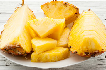 slices of a pineapple on white wooden background