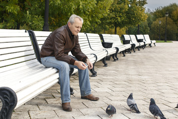 elderly man feeding doves in a deserted park