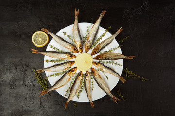 Smoked baltic herring with filings and thyme on a white plate. Top view, flat lay.