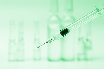 glass syringe in front of medicine bottles in green tone