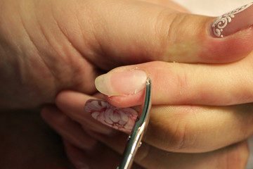 A student at the training courses of a manicure prepares the hand of a lady client with a manicure scissors for cuticles before applying shellac