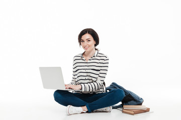 Portrait of a smiling teenage girl with backpack using laptop