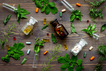 Herbal medicine pattern. Leaves, bottles and pills on wooden background top view