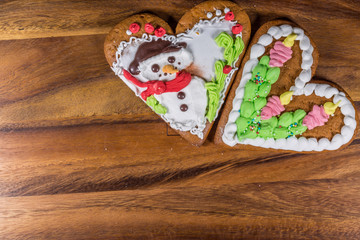 Two Gingerbread heart shape cookies and spruce branch on wood