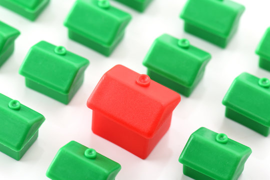 Large Red House Standing Out From Small Green Houses