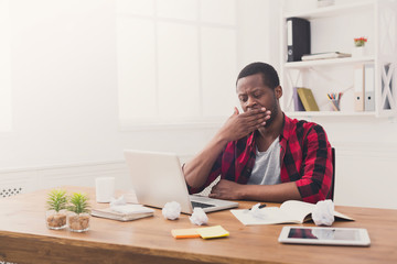 Sleepy black businessman in casual office, work with laptop