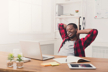 Young relaxed businessman with laptop in modern white office