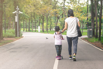 Mother take care child ride scooter in a park