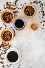 Cup of black coffee near coffee beans and cinnamon on grey background top view copyspace
