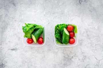 Healthy meal in containers. Summer salad with tomato and cucumber on grey background top view copyspace