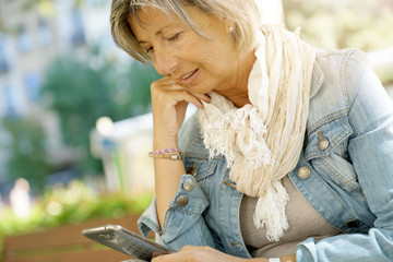 Senior woman reading message on smartphone, citylife