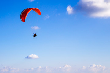 Paraglider flies in the blue sky.