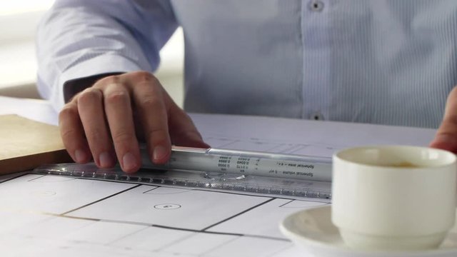 architect with ruler measuring blueprint