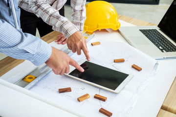 Engineering is looking tablet on a blueprint. To prepare for field work