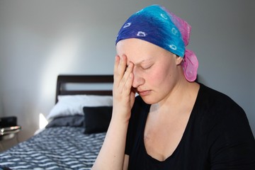 Young cancer patient in a headscarf rubs face with stress - obrazy, fototapety, plakaty
