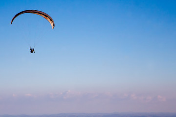 Paraglider flies in the blue sky.