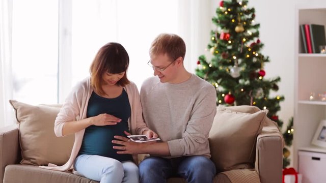 happy couple with ultrasound images at christmas