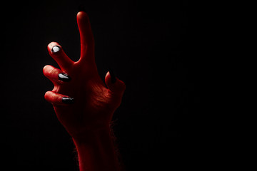 Red devil creepy halloween hand on a black background - obrazy, fototapety, plakaty