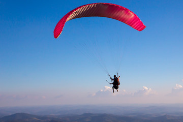 Naklejka na ściany i meble Paraglider flies in the blue sky.