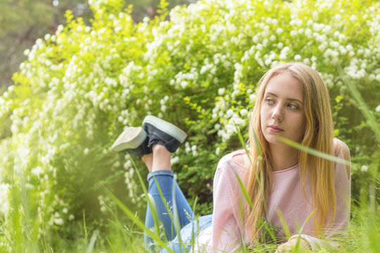 Cute blonde teenage-girl dreaming on a sunny day on the grass