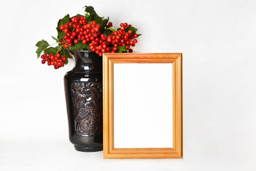 Wooden frame and the branch of viburnum in a vase.